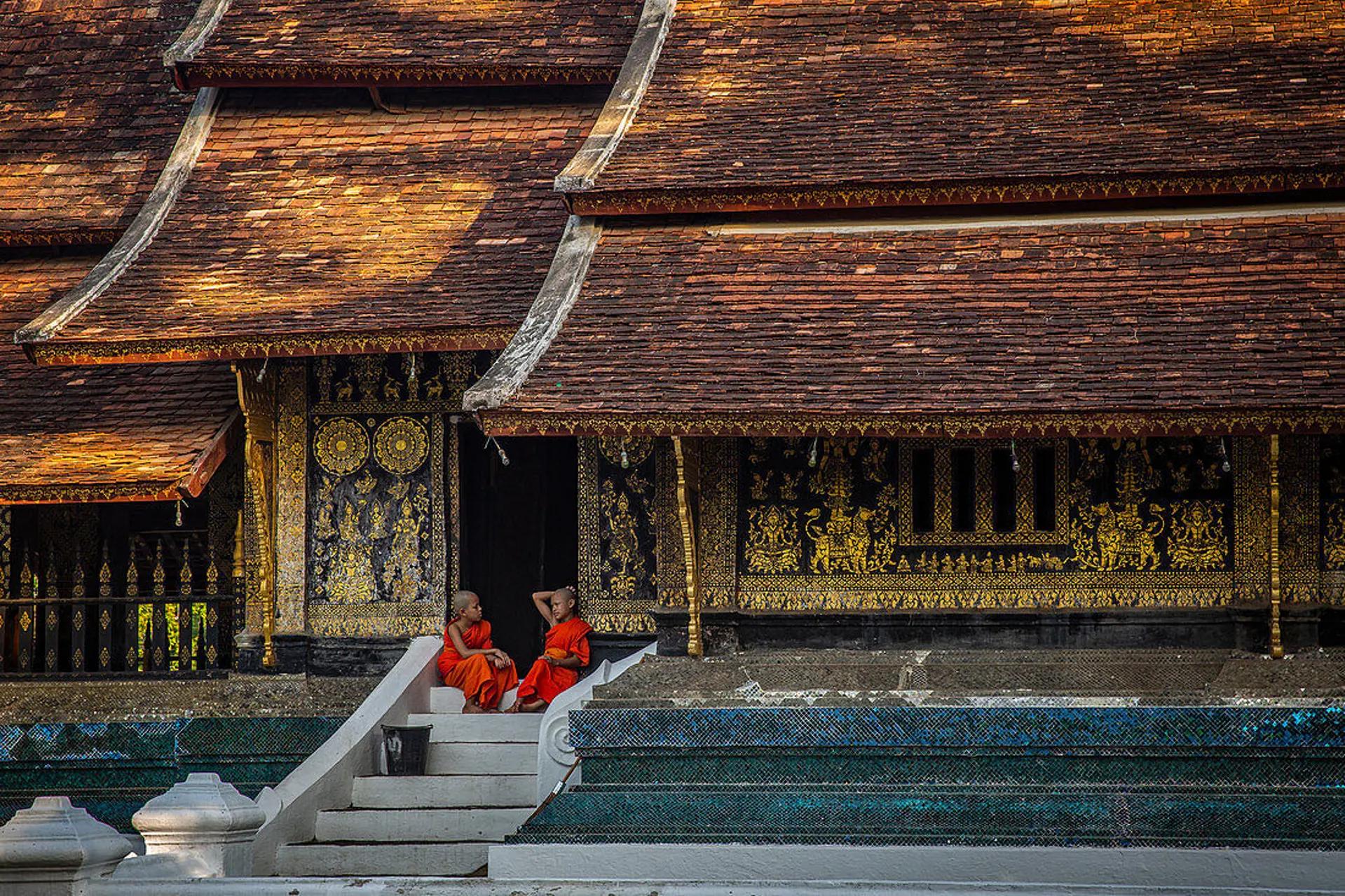 Two young Buddhist monks laughing together outside a temple in Laos