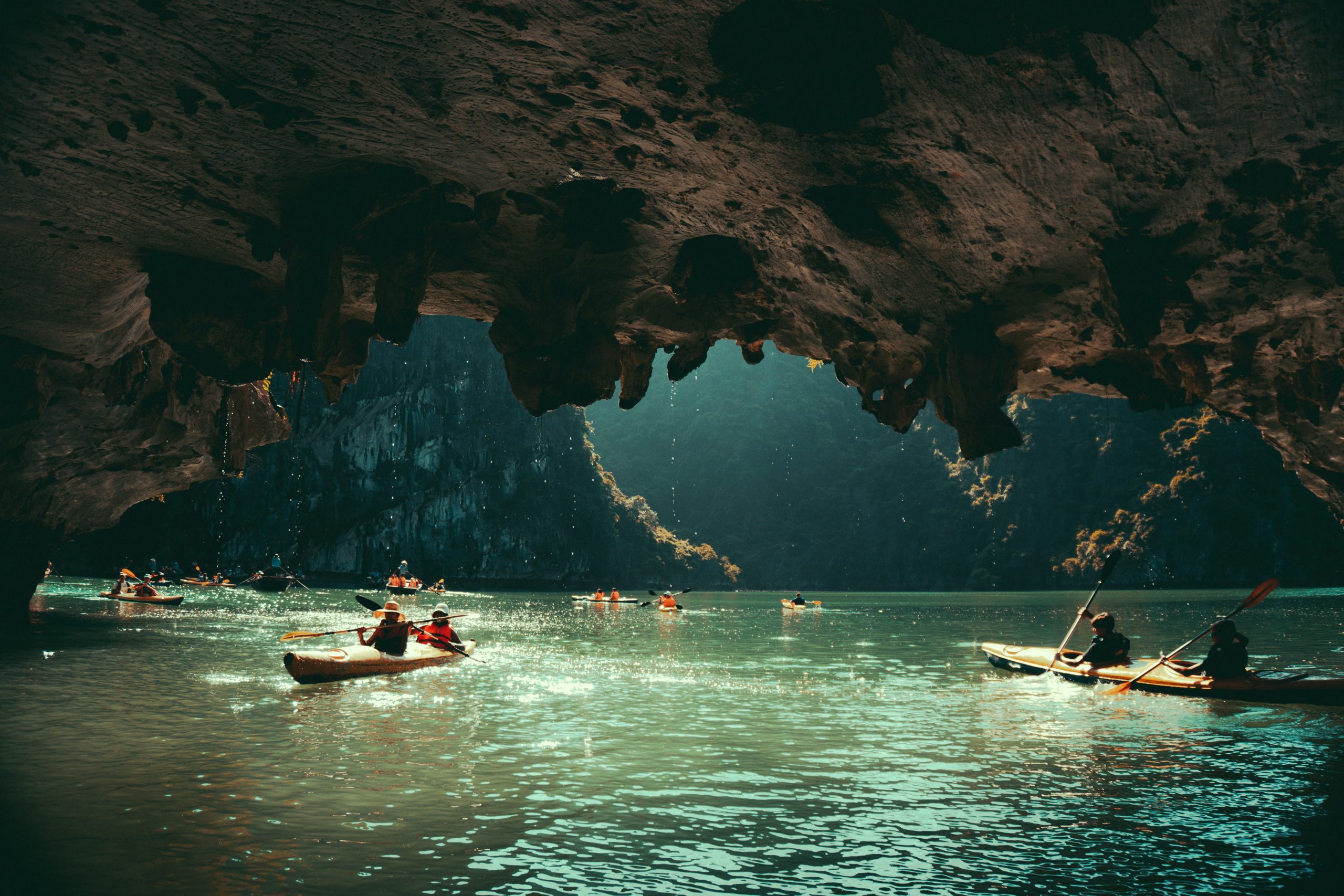 Travellers kayaking out of a limestone cave in Ha Long Bay, Vietnam