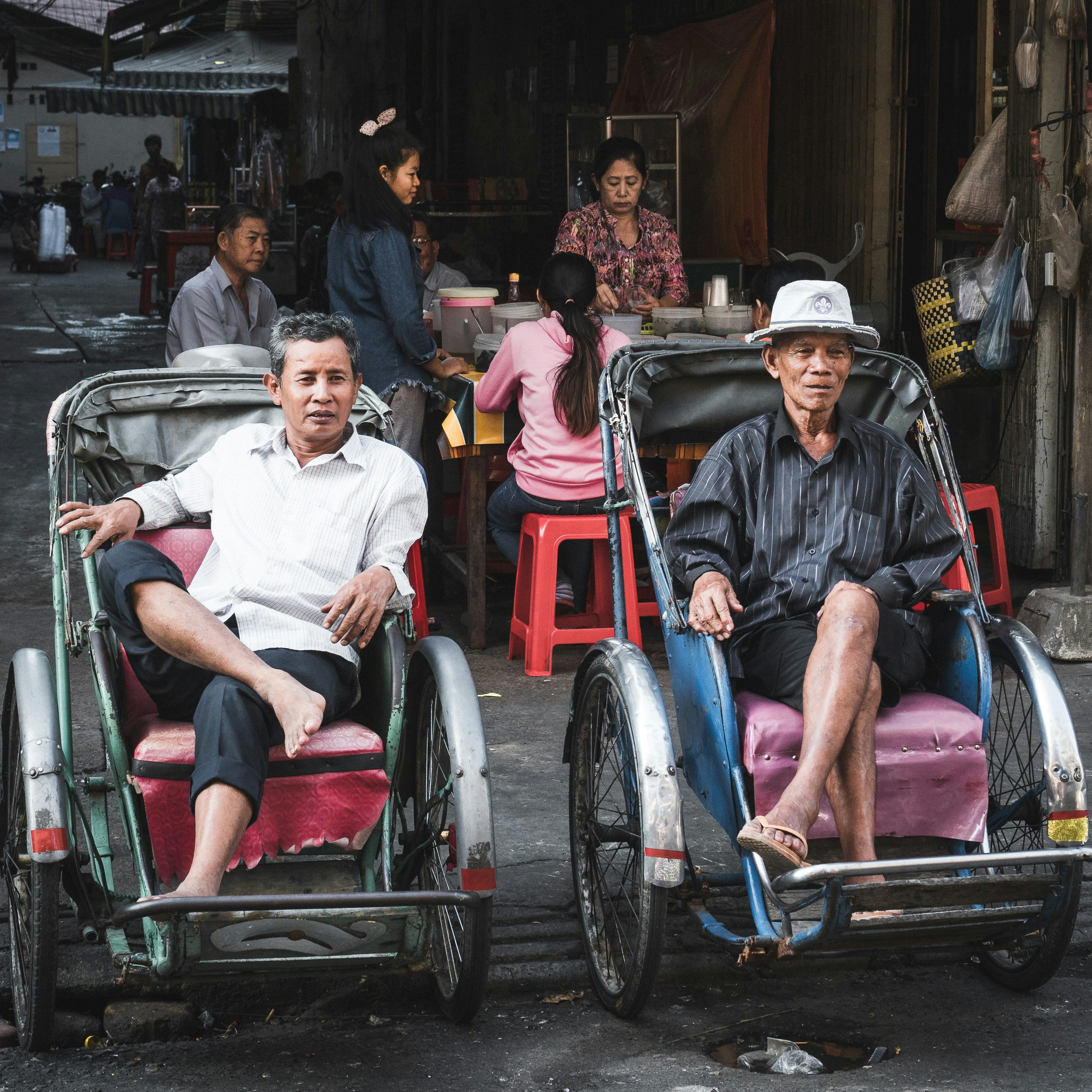 Cambodian men sitting in parked cyclos and watching the street in Phnom Penh