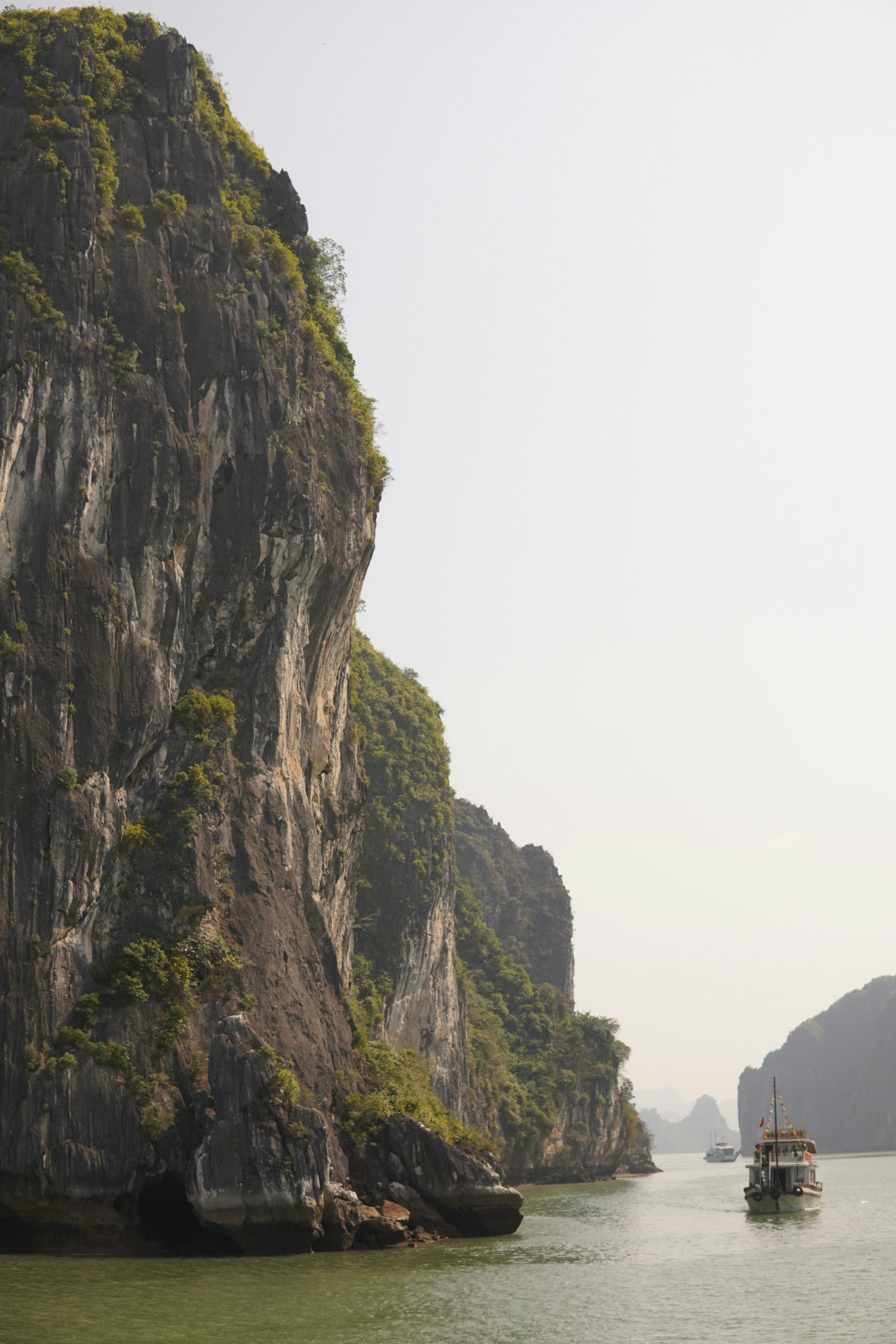 Cruise boat sailing between limestone karsts in Ha Long Bay, Vietnam