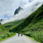 Two motorbikes riding along a scenic mountain road in Northern Vietnam