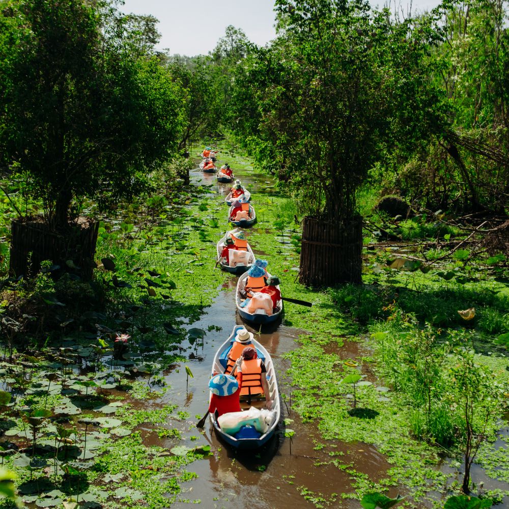 Boats carrying passengers along a green Mekong Delta canal